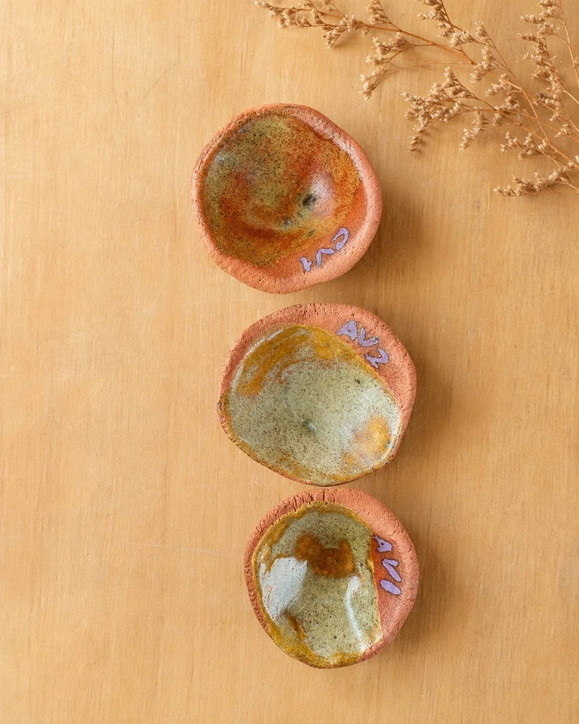 Muestras de esmaltes minerales y cristalizaciones sobre cuencos de barro rojo en el taller